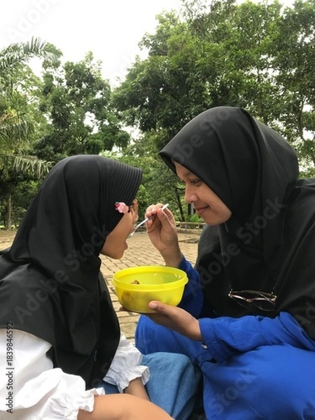 Obraz Mom Feeding Her Daughter Outside in a Natural Environment