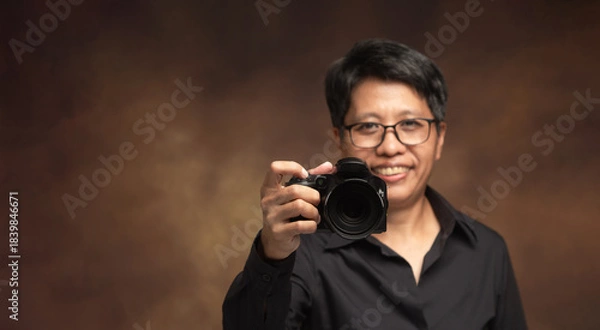 Obraz Photographer holding camera forward in studio portrait.