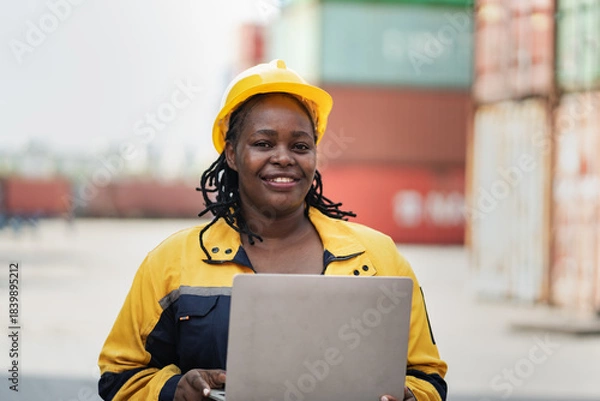 Obraz Portrait African woman logistics workers use notebook computer checking container	