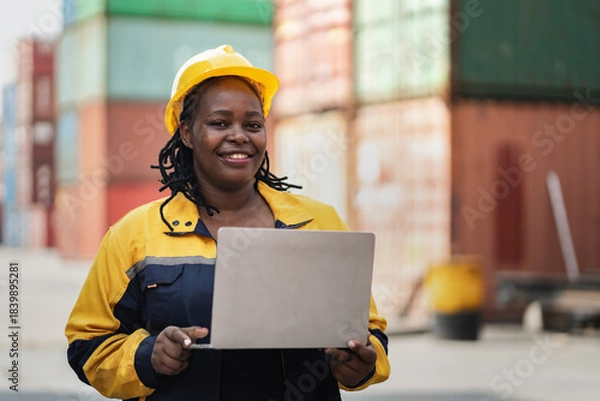 Obraz Portrait African woman logistics workers use notebook computer checking container	