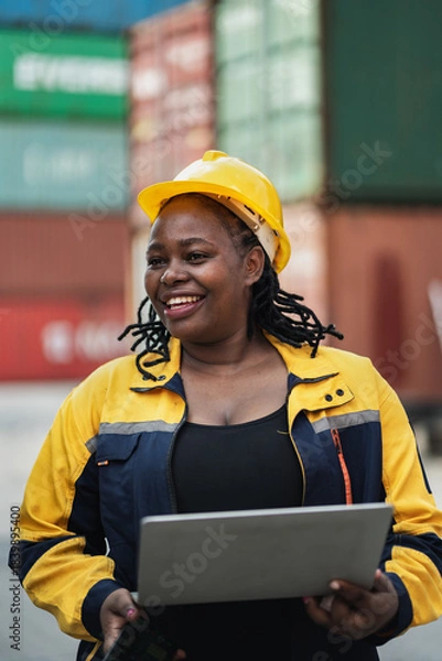 Obraz Portrait African woman logistics workers use notebook computer checking container	