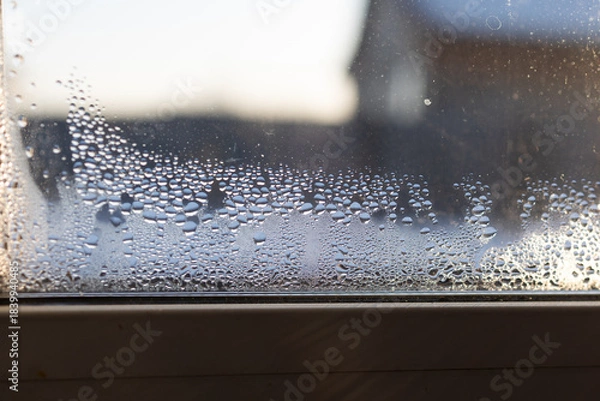 Obraz Water droplets accumulate on the interior of a glass window, revealing high humidity. This suggests inadequate air circulation which can lead to mold and mildew growth indoors.