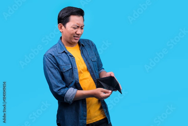 Obraz Sad Young Asian Man With an Empty Wallet, Showing Stress on Blue background