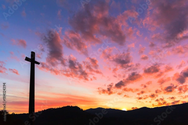Fototapeta Cross silhouette with the orange from red sunset sky as background.