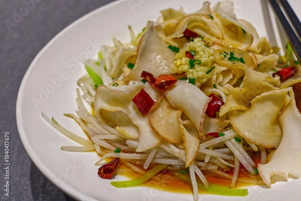 Fototapeta A close-up of a cold Chinese appetizer featuring thin slices of pork ear/tendon and bean sprouts tossed in a dark sauce.