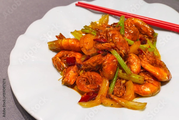 Fototapeta A close-up of whole shrimp stir-fried in a rich spicy sauce with sliced onions, celery, and dried chili peppers.