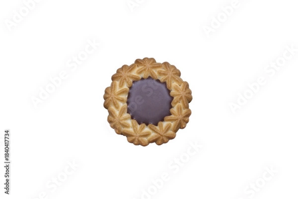 Fototapeta A top-down close-up of a single, golden-brown butter cookie with a decorative flower-like edge and a solid dark chocolate center. 