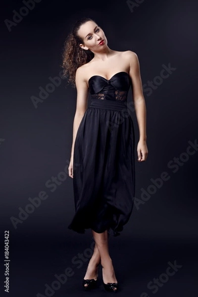 Fototapeta Portrait of a fashionable elegant girl in a black dress with red apple on a dark background in a photo studio. Evening image. Evening Dress. Concept of an elegant image for a romantic date or a party