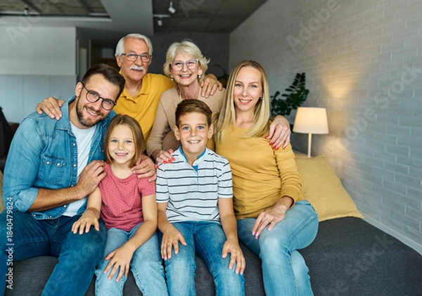 Obraz Portrait of a three generation famili, grandparents, parents and children sitting on sofa and having fun posing at home