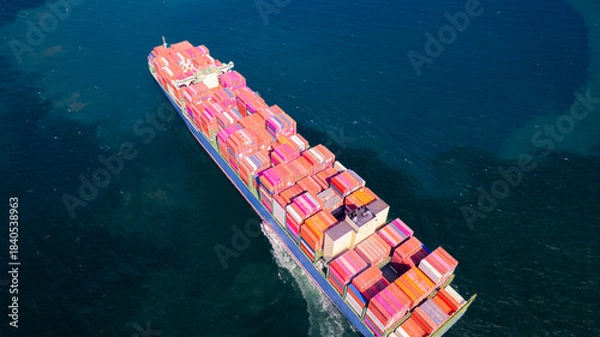 Fototapeta A container ship, fully loaded with goods, sails out to sea, delivering products to various locations around the world.