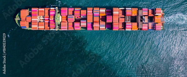 Fototapeta A container ship, fully loaded with goods, sails out to sea, delivering products to various locations around the world.