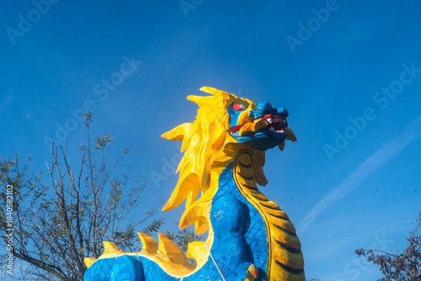 Fototapeta Dettaglio di una giorstra per bambini a forma di drago blu e giallo con il cielo sullo sfondo