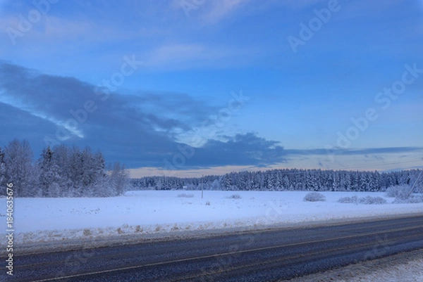 Fototapeta Snowy field with a blue sky in the background