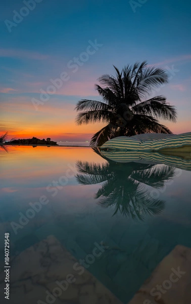 Fototapeta View from luxury villa at dusk, pool lighting, sun loungers for sunbathing, umbrellas from the sun, pillows for swimming in the pool, palm tree on background
