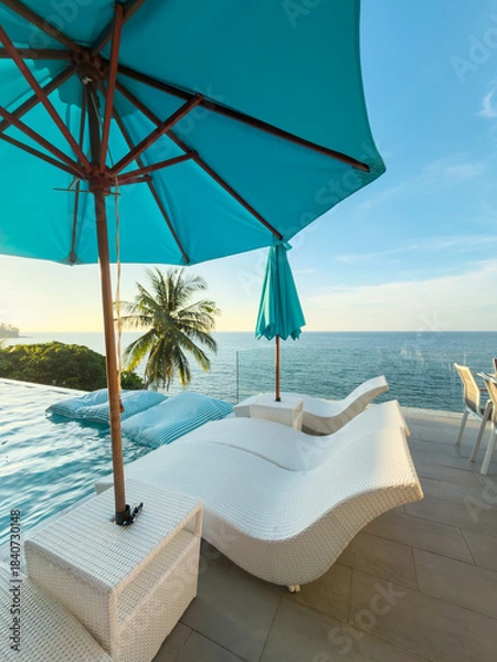 Fototapeta View from luxury villa at sunset, sun loungers for sunbathing, umbrellas from the sun, pillows for swimming in the pool, palm tree on background