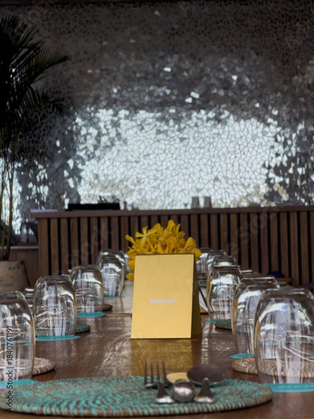 Fototapeta table setting in the restaurant, a sign saying reserved on the table, yellow flowers, glasses turned upside down waiting for guests