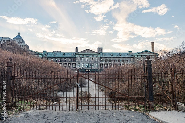 Obraz Abandoned institutional building behind rusty gate.