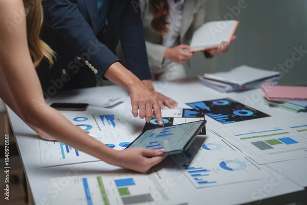 Fototapeta Business professionals analyzing financial data using tablet and charts