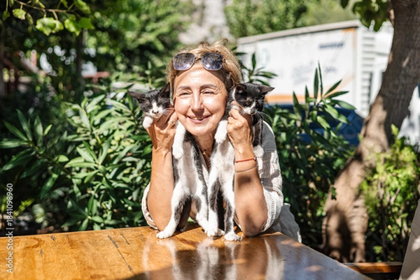 Obraz middle-aged woman holds a small black and white cat in her arms
