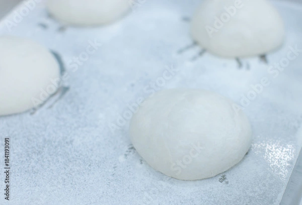 Fototapeta Smooth ball of fresh dough rests on floured stainless steel table in clean food preparation area, Factory production line baking preparation professional kitchen workflow industrial technology concept