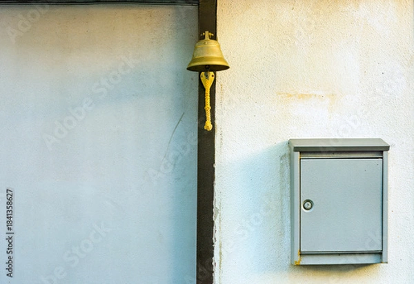 Obraz copper bell and a metal letterbox both attached to the front of a house