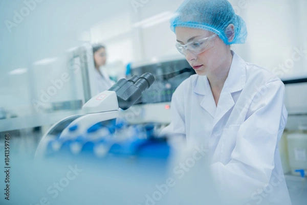 Fototapeta Scientist conducts research in a laboratory during daylight hours while using a microscope