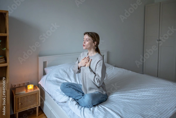 Fototapeta Reflective woman practicing breathing exercise on bed, calming nervous system after days of mental overload. Peaceful female focuses on self-soothing, seeking inner balance, relieve stress at home.