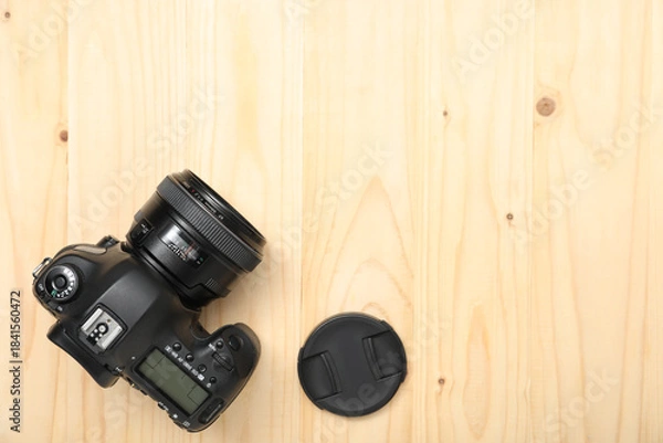 Obraz Professional camera and lens cover on wooden background, top view with space for text. Photographer's equipment