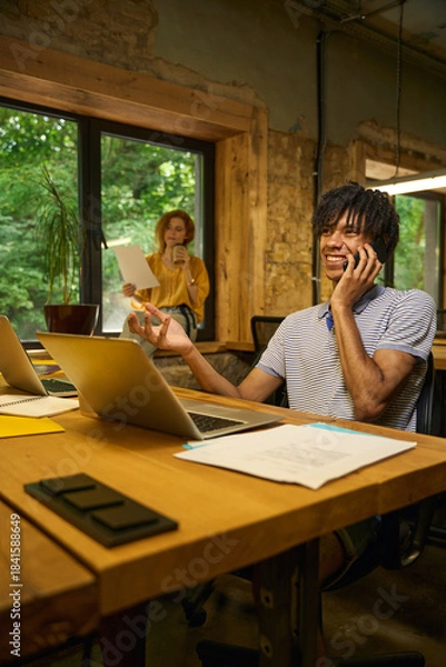 Obraz Man on a phone call while working on laptop