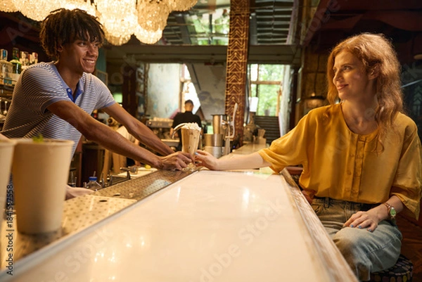 Obraz Two people exchanging drinks at a bar