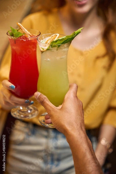 Obraz Two people holding colorful cocktails together