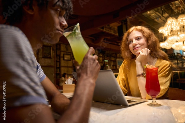 Obraz Man sipping a drink while talking to a colleague