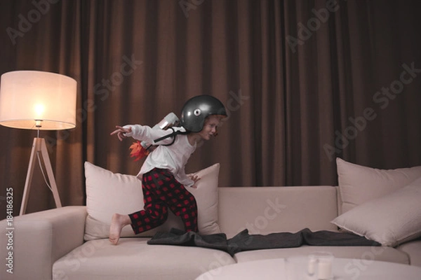 Fototapeta Funny cute dreamer kid boy wearing rocket pack made from plastic bottles pretending to be an astronaut