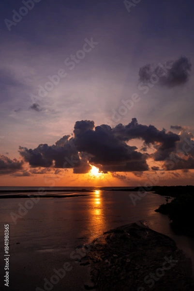 Fototapeta Stunning Sunset Over Calm Ocean With Silhouetted Shoreline, Dramatic Clouds, And Dusk Light