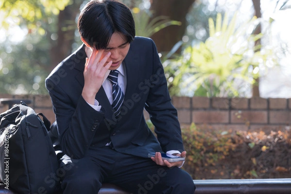 Obraz 外回りの営業でベンチに座って悩む男性ビジネスマン　営業成果が未達で困る頭を抱える