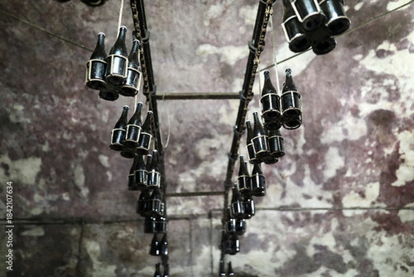 Obraz Many bottles hanging upside down on rack in cellar