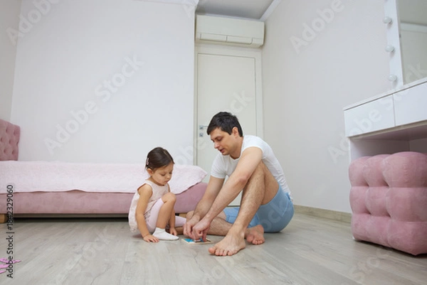 Fototapeta Father and daughter enjoying time together, solving a puzzle on the bedroom floor