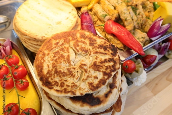 Obraz Pita and stuffed cabbage rolls prepared on grill at a Christmas market where various traditional dishes are served.