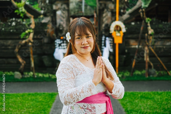 Fototapeta Balinese Woman in Traditional Kebaya with Namaste Gesture in Front of Pura