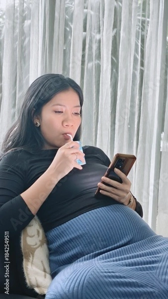 Obraz Pregnant Woman Drinking Nutritious Milk While Relaxing and Browsing Her Smartphone