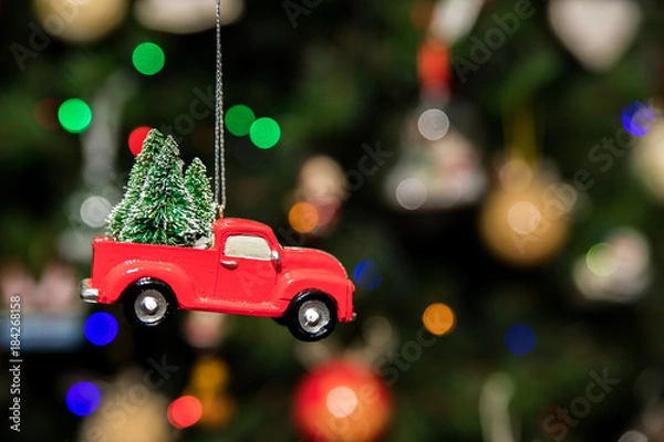 Fototapeta Red pickup car with Christmas tree hanging on Christmas tree