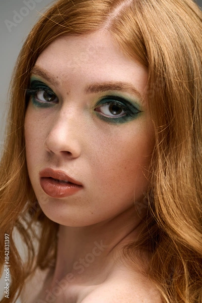 Obraz Bold eye makeup transforms a beautiful redhead in a grey studio