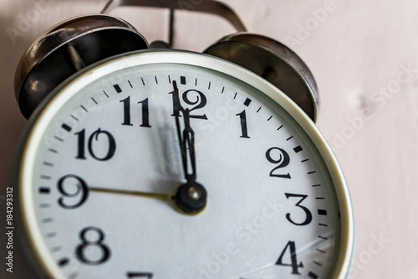 Fototapeta A close-up of a clock showing 12.00 hours on rustick bacground. Concept New Year.