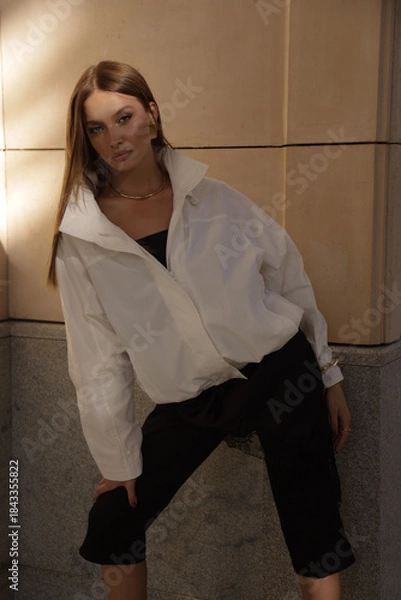 Fototapeta beautiful woman with dark hair in elegant clothes posing on the city street