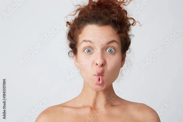 Obraz Cropped shot of funny cute young woman with curly hair and healthy skin making fish face with lips and having fun isolated over white wall Comical expression