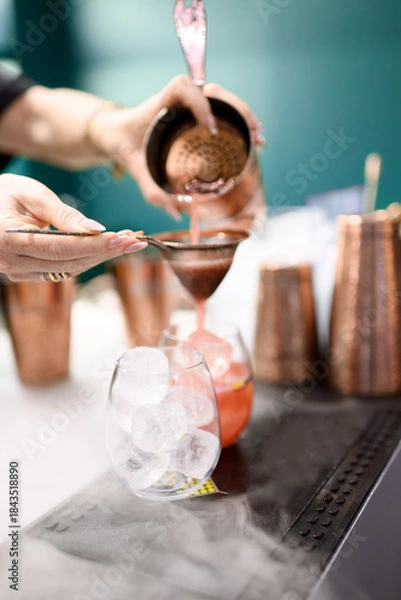 Obraz Bartender Using Copper Tools to Pour Red Cocktail
