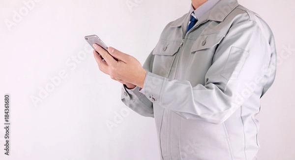 Obraz スマホを操作する作業服の男性