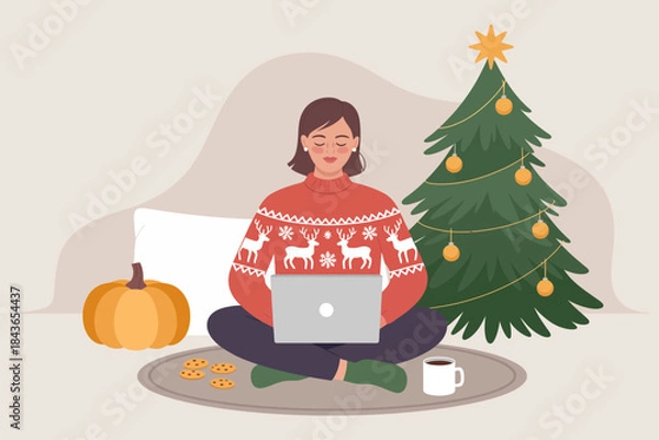 Obraz A woman in a festive sweater is working on her laptop surrounded by holiday elements, including a beautifully decorated Christmas tree and delicious cookies, exuding cozy winter vibes.