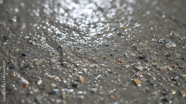 Obraz Wet asphalt road surface with small stones and pebbles reflecting light