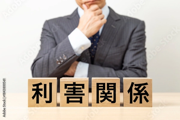 Fototapeta 「利害関係」と書かれたブロックとビジネスマン